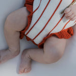 Picnic Pinstripe | Knit Ruffle Romper showing soft knit fabric and adorable ruffle details on a baby's legs.