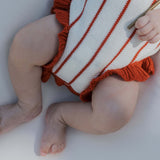 Picnic Pinstripe | Knit Ruffle Romper showing soft knit fabric and adorable ruffle details on a baby's legs.