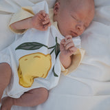 Baby sleeping in a onesie with a lemon design on a white background