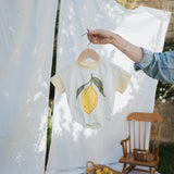 Baby onesie with lemon design hanging on a line outdoors