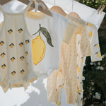 Children's clothing with lemon designs hanging on a line outdoors.
