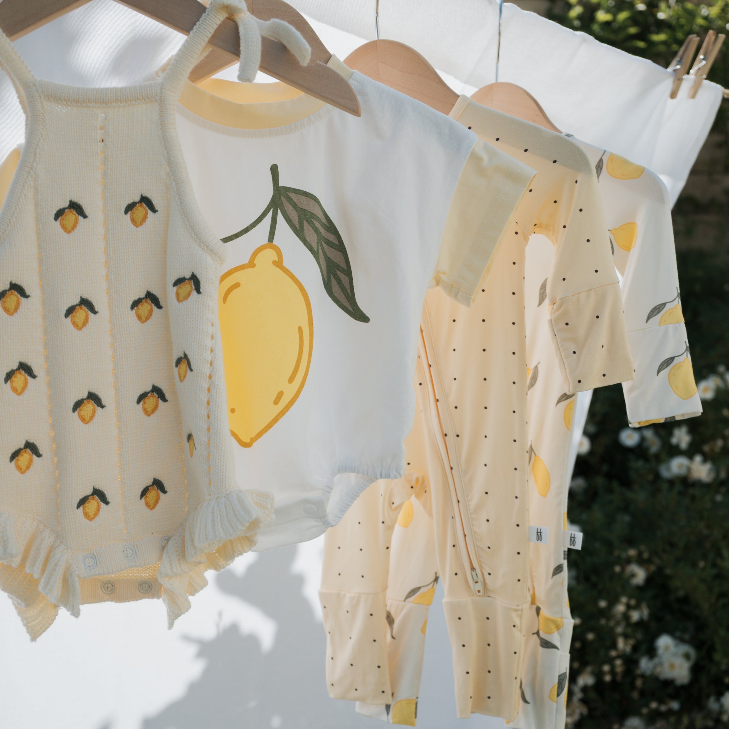 Lemon Bamboo Zip Pajamas displayed on hangers in soft yellow colors, showcasing cozy designs for little ones.