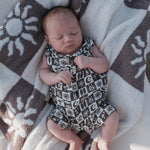 Baby wearing Summer Check | Muslin Tank Romper on a cozy blanket with sun patterns.