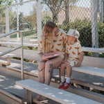A woman and child sitting on bleachers in matching Hot Dogs | Women's Bamboo Short Set, enjoying the sunny day.