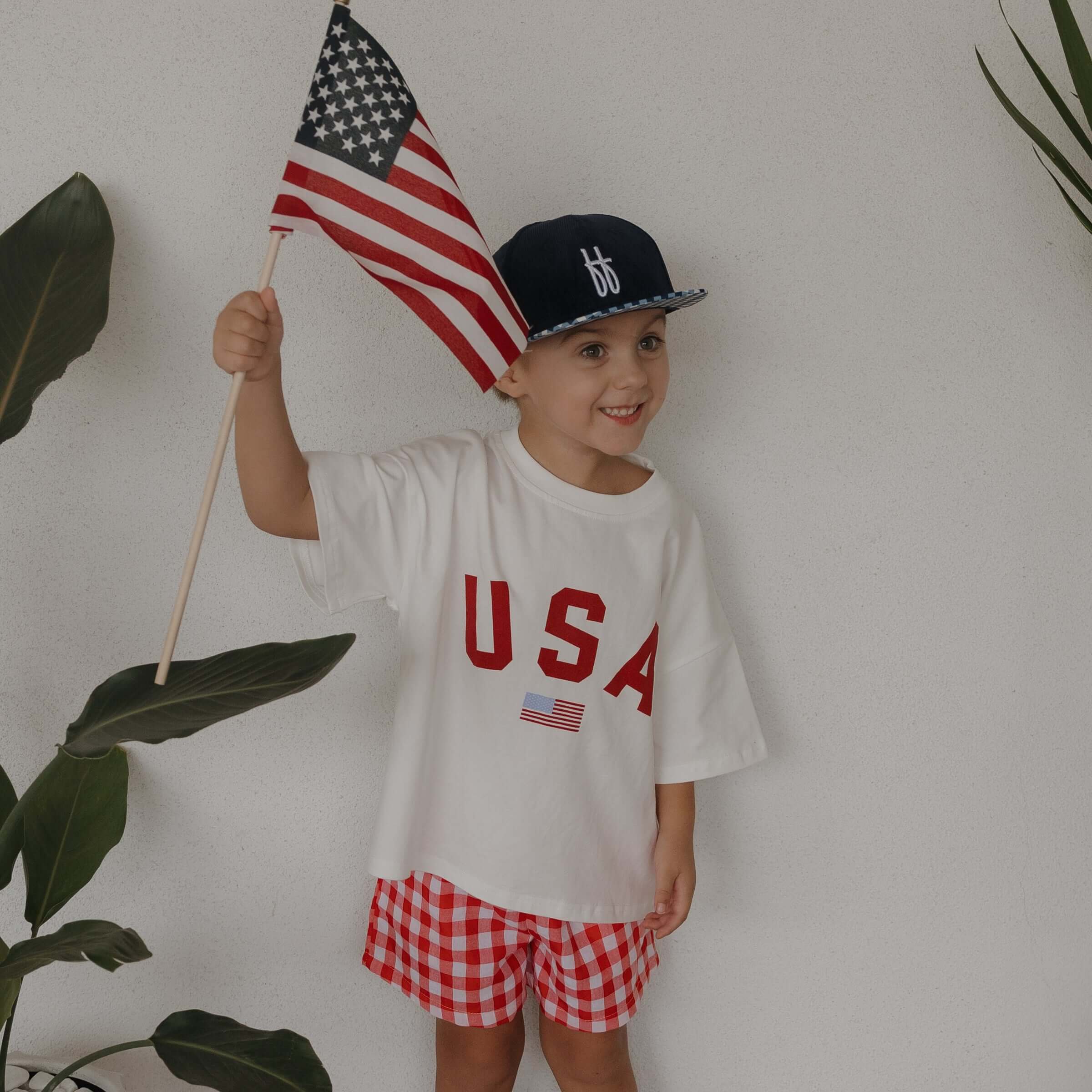 Child wearing USA cotton tee and holding American flag, ideal for USA Mommy & Me matching outfits.