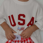 Child wearing USA T-shirt paired with red checkered shorts, perfect for USA Mommy & Me outfits.