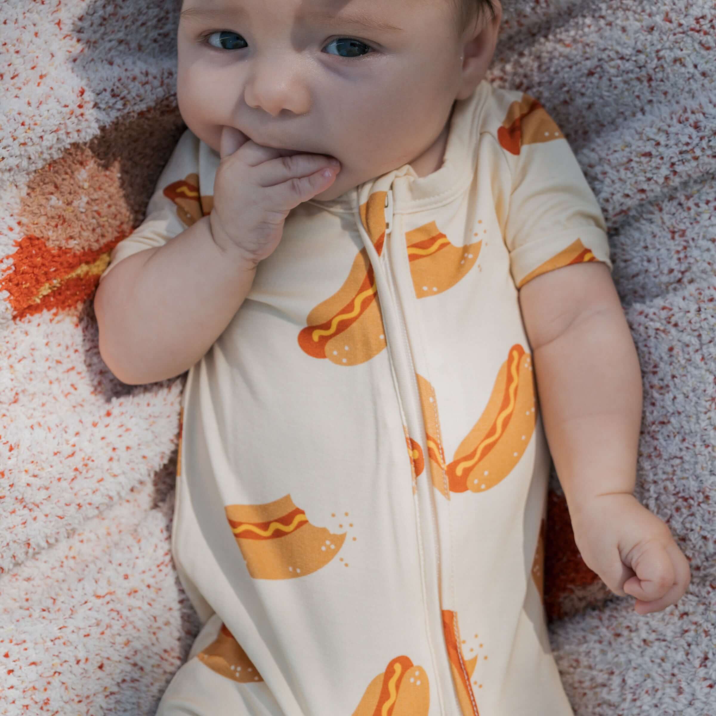 Baby wearing Hot Dogs | Shortie Bamboo Zip romper, showcasing fun hot dog prints | milk & baby.