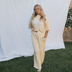 A woman wearing a Women's Boxy Tee Lounge Set in a light yellow color, standing on grass with a relaxed pose.