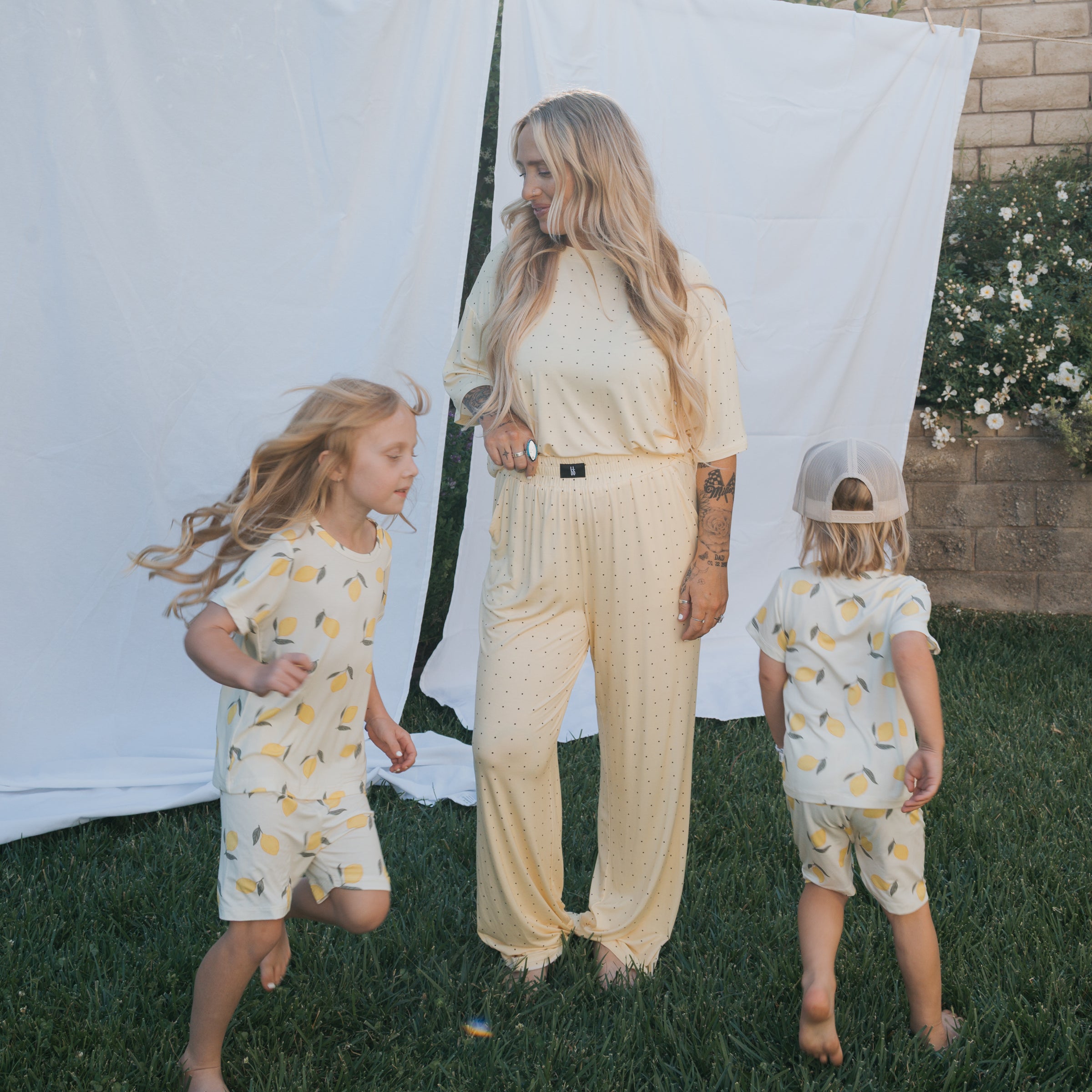Women's Boxy Tee Lounge Set featuring a woman and children in coordinating lemon-patterned loungewear outdoors.