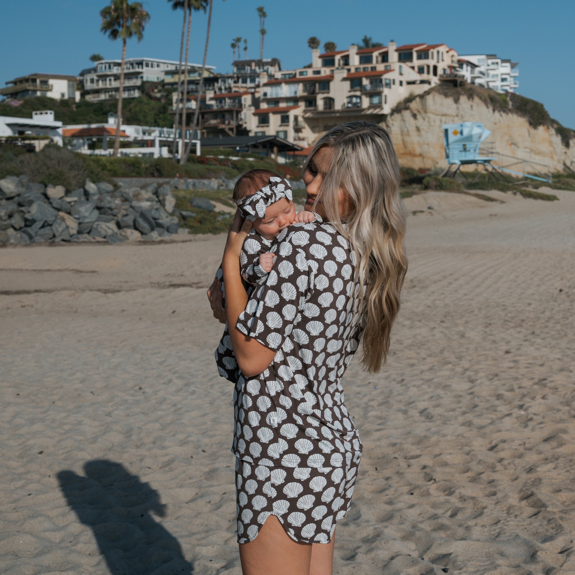 A woman wearing a Women's Bamboo Short Set with a baby on a beach, showcasing a stylish and comfortable summer look.