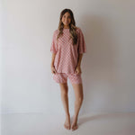 Woman wearing a pink checkered outfit against a plain background
