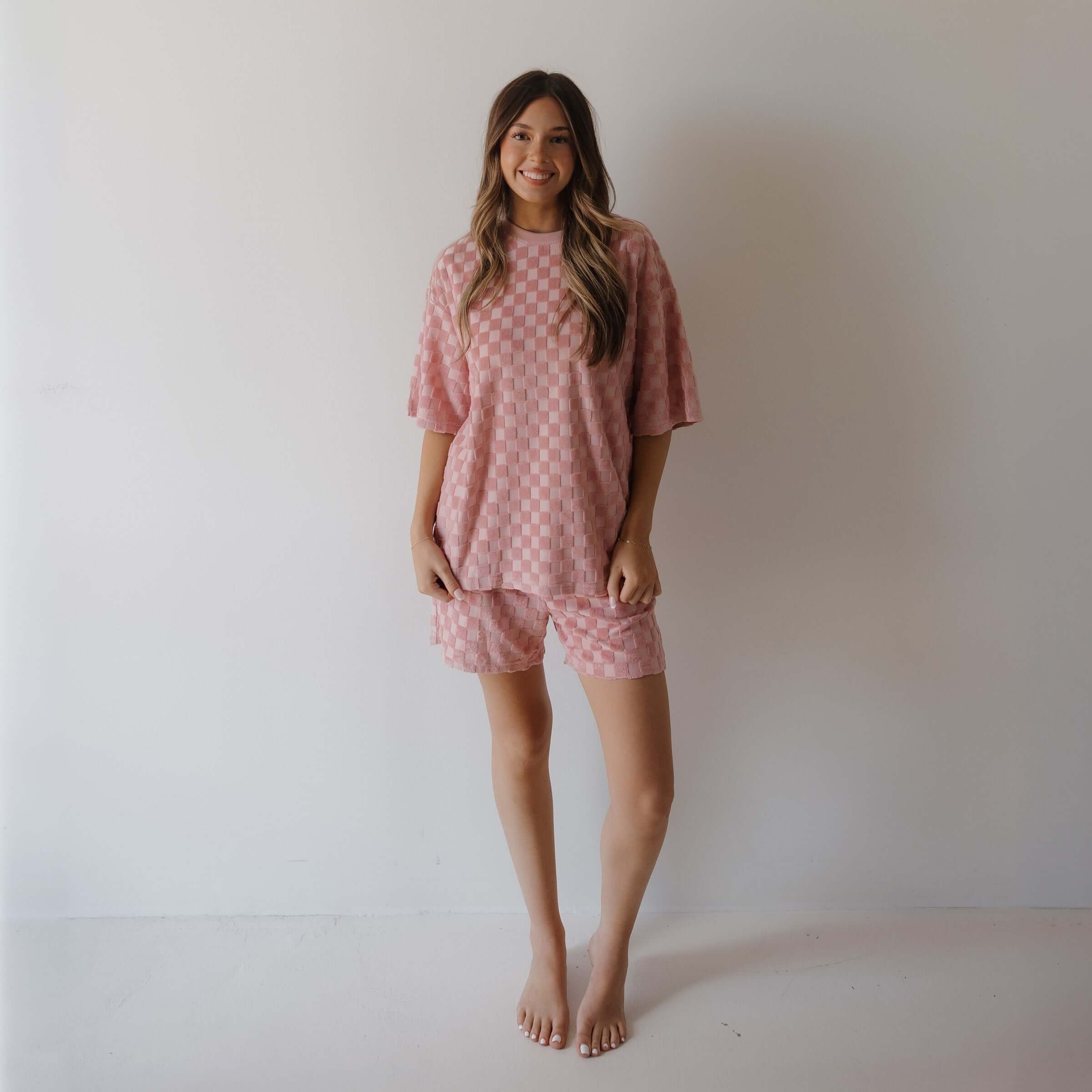 Woman wearing a pink checkered outfit against a plain background