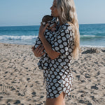 Woman wearing Women's Bamboo Short Set holding a baby on the beach with seashells pattern in warm weather.