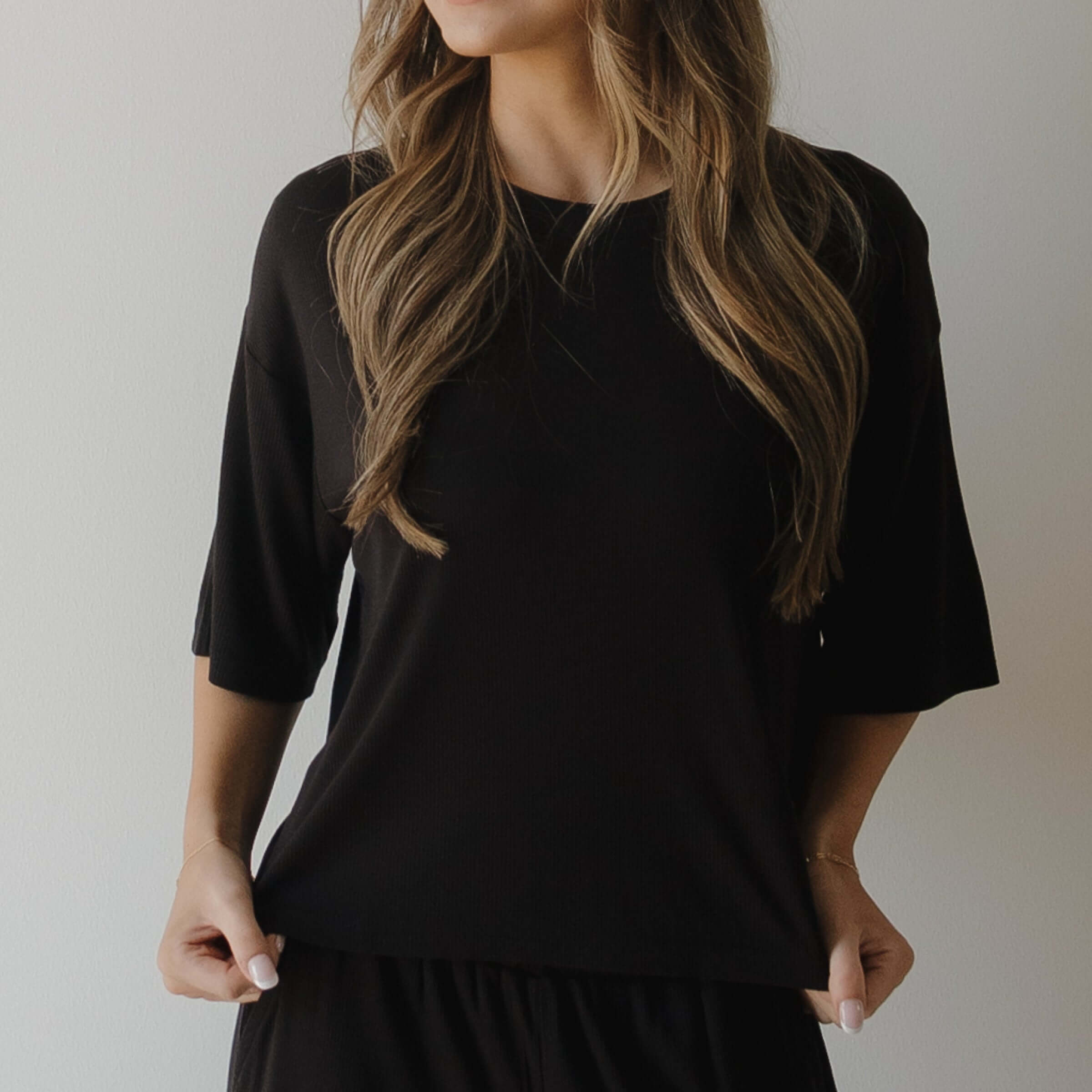 Person wearing a black pajamas against a neutral background