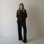 Woman wearing black pajamas against a plain background