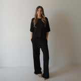 Woman wearing black pajamas against a plain background