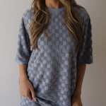 Person wearing a gray blue checkered set against a neutral background