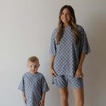 Two people wearing matching gray blue  checkered outfits against a plain background