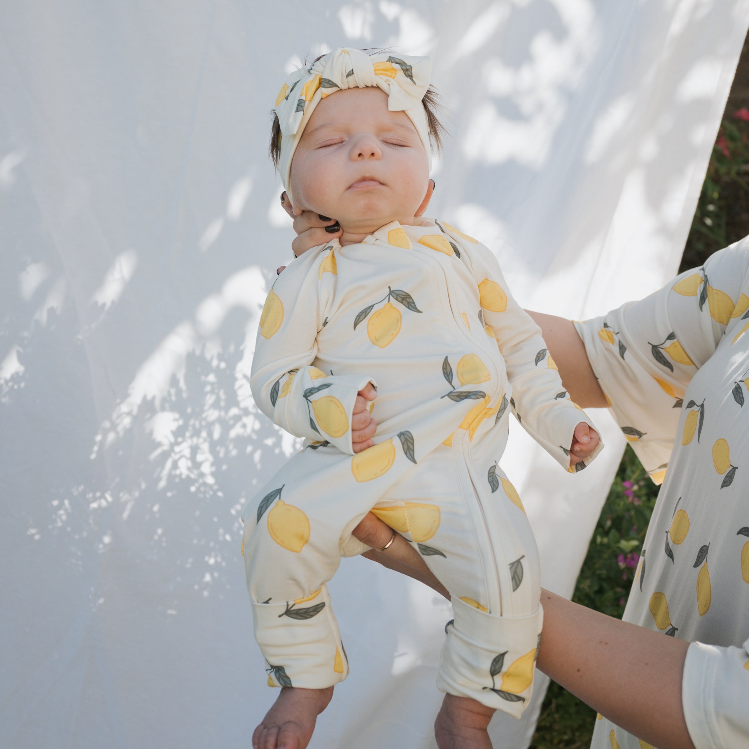 Baby wearing Lemon Bamboo Zip Pajamas with lemon print and headband, showcasing softness and comfort.