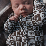Baby peacefully sleeping in Summer Check Bamboo Zip Pajamas with unique print and zipper detail.