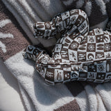 Cozy baby in Summer Check Bamboo Zip Pajamas on a soft blanket.
