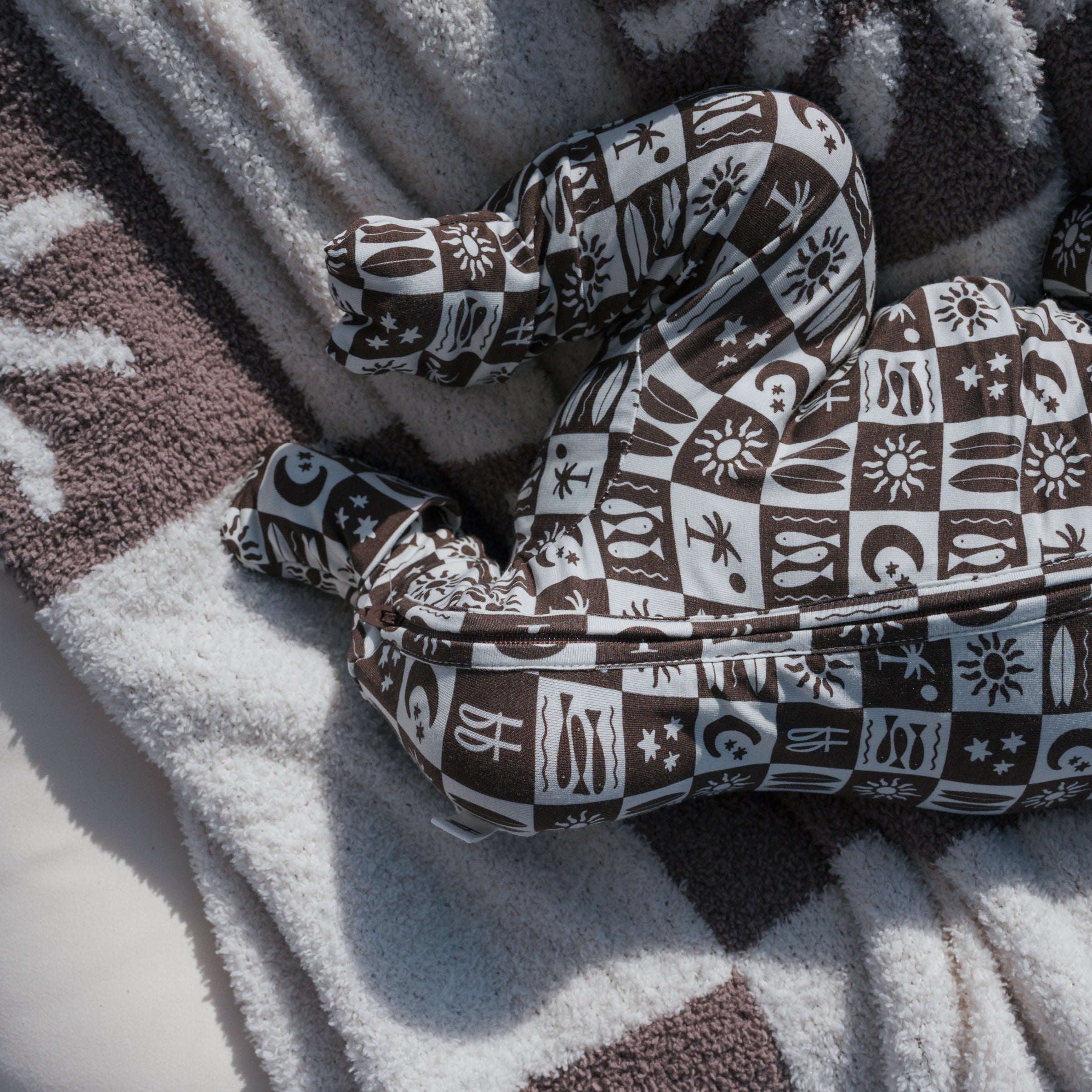 Cozy baby in Summer Check Bamboo Zip Pajamas on a soft blanket.