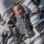 Baby peacefully sleeping in Summer Check Bamboo Zip Pajamas on a cozy blanket.